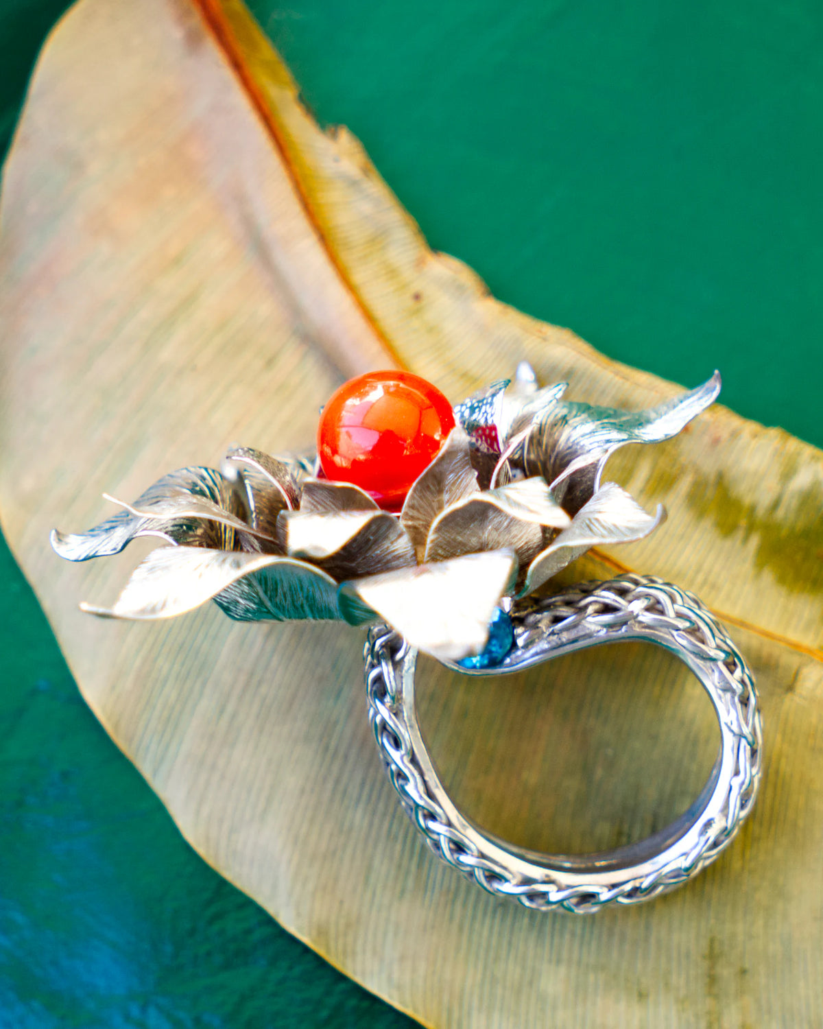 The Suzy ring, in rhodium-plated solid silver 950, featuring a red Mediterranean coral pearl and blue topazes, from the Caprice collection | Honu