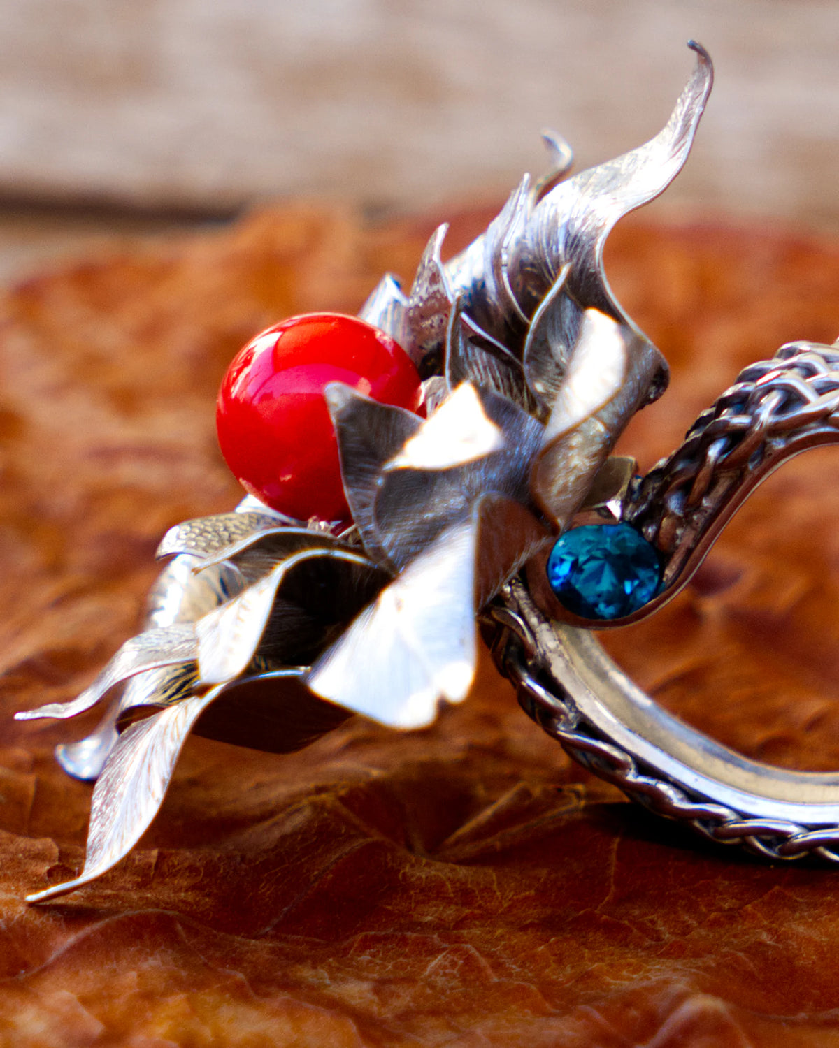 The Suzy ring, in solid silver 950‰ with rhodium plating, featuring a red Mediterranean coral pearl and blue topazes, from the Caprice collection | Honu