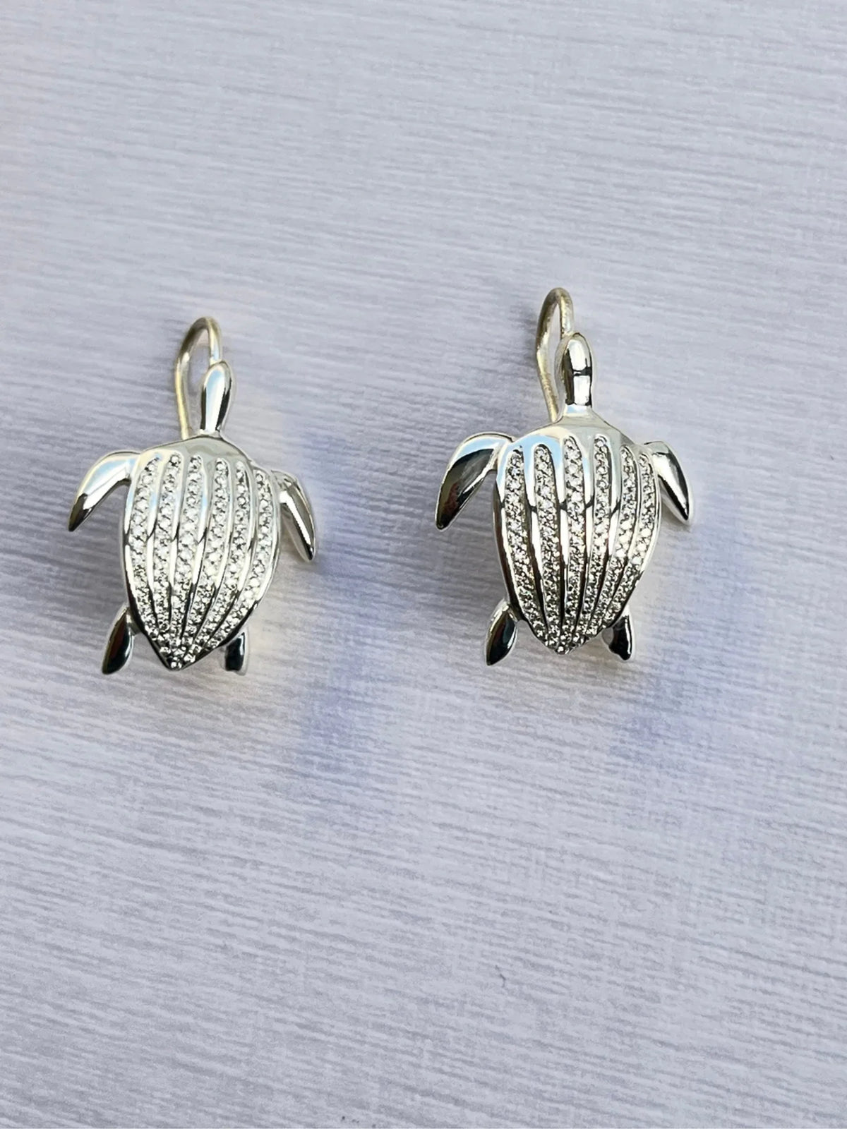 Les boucles d'oreilles Totem Luth, diamants incolores sur argent massif, la paire vue de dessus, crochets visibles | Honu