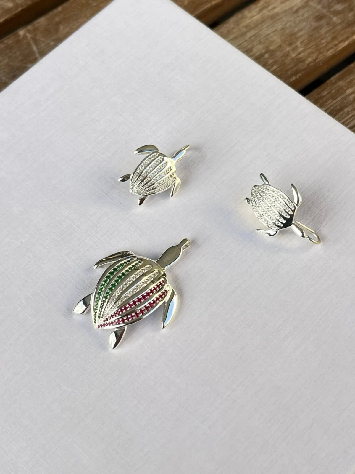 Les boucles d'oreilles Totem Luth, diamants incolores sur argent massif, posées sur une toile blanche avec le pendentif Totem Luth Italia | Honu