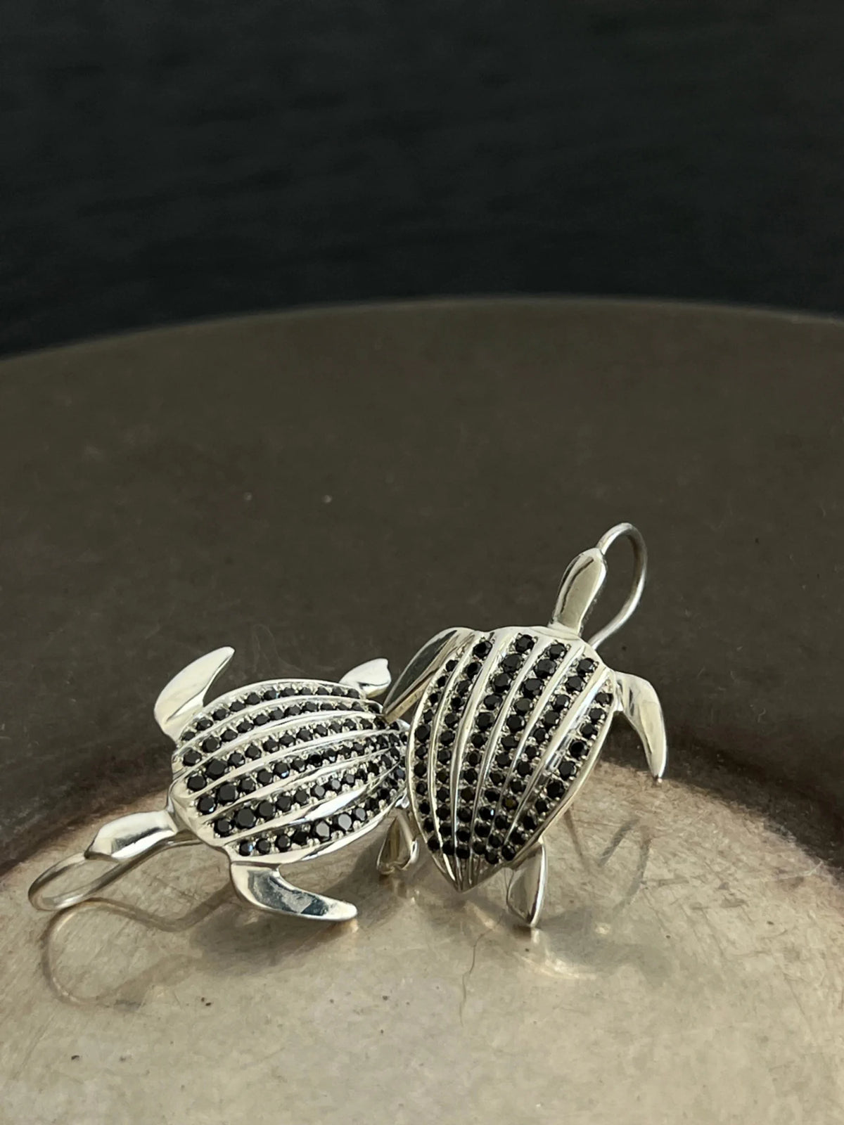 Les boucles d'oreilles Totem Luth, diamants noirs sur argent massif, en gros plan, crochets visibles | Honu