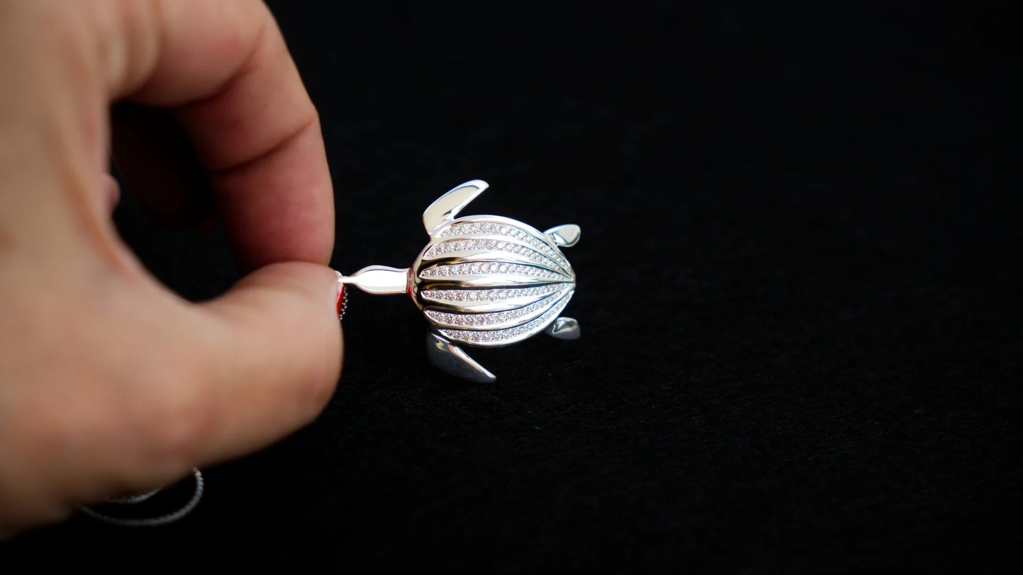 Le pendentif Totem Luth tenu entre les doigts, en gros plan, de la collection Totem Luth | Honu