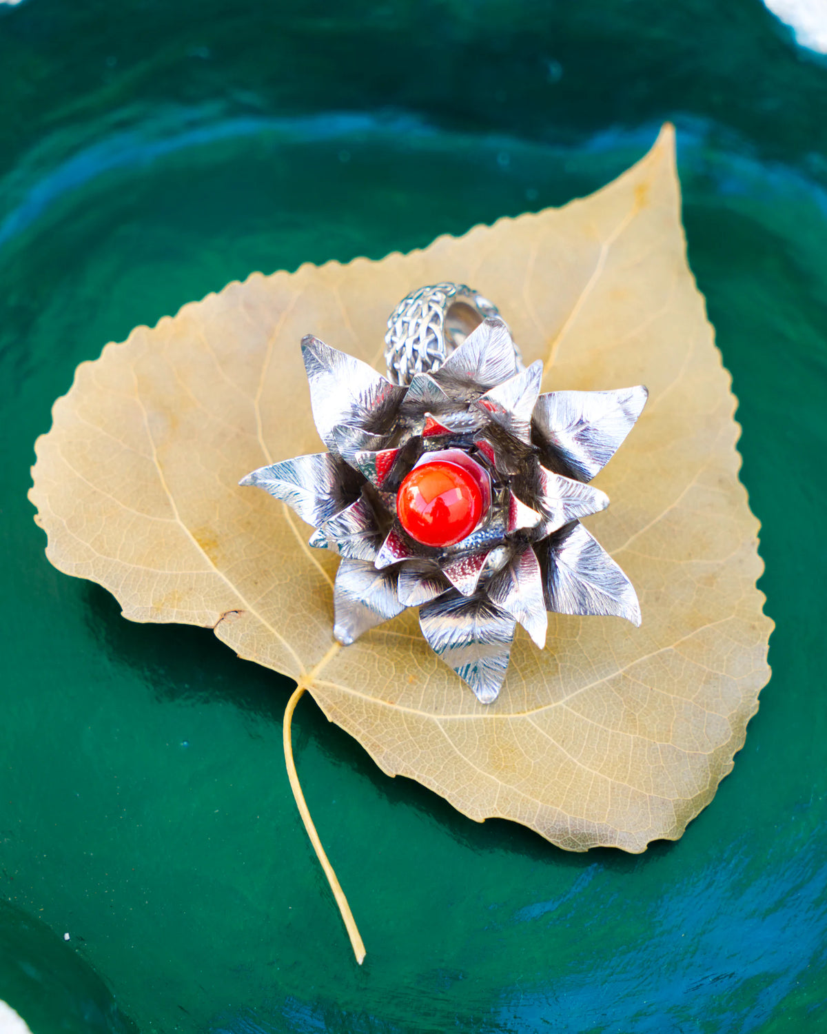 The Suzy ring, in rhodium-plated solid silver 950, featuring a red Mediterranean coral pearl and blue topazes, from the Caprice collection | Honu