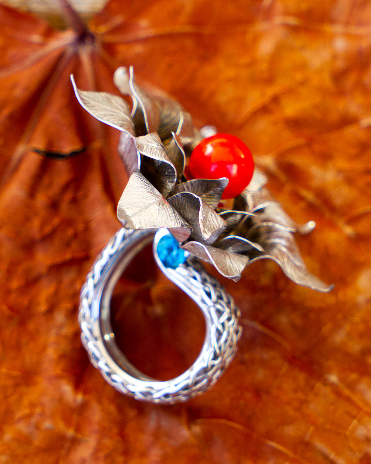 The Suzy ring, in solid silver 950‰ rhodium-plated, featuring a red Mediterranean coral pearl and blue topazes, from the Caprice collection | Honu
