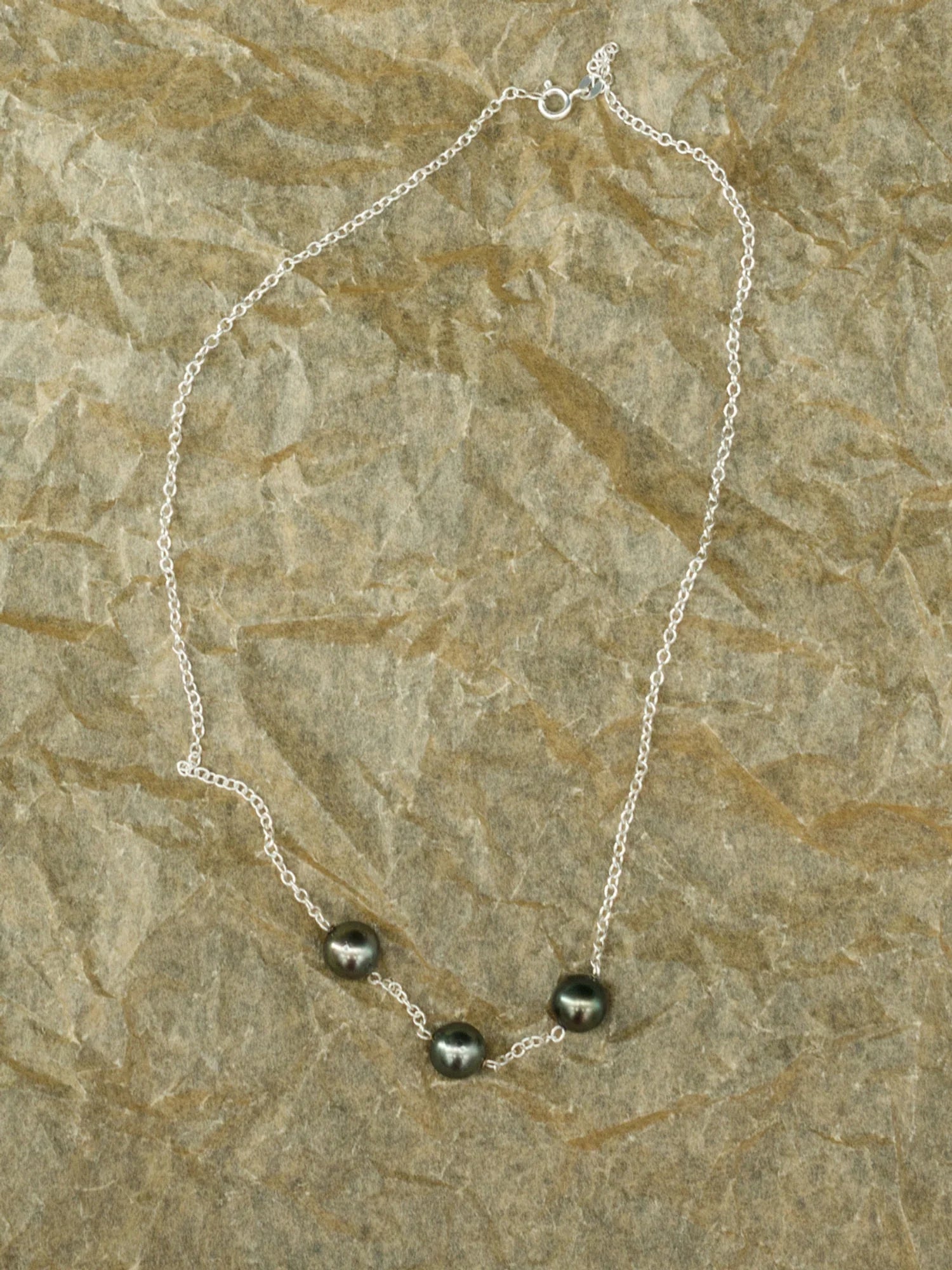 The Latitude 9.42 necklace, featuring three Tahitian pearls set against a light-coloured stone, from the Instinct | Honu Collection