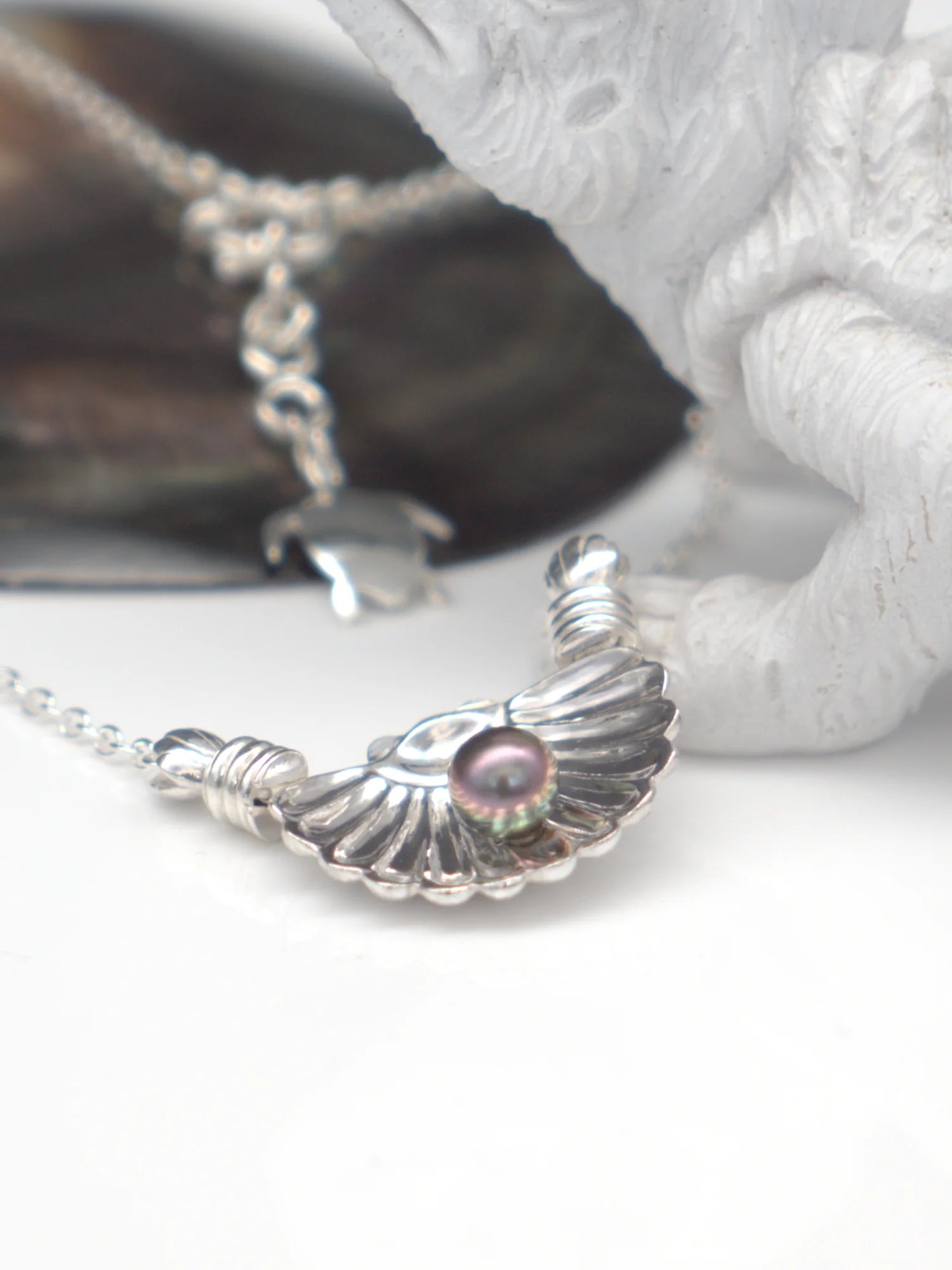 Pendentif coquillage artisanal en argent massif 950 avec une perle de Tahiti foncée sur chaîne.