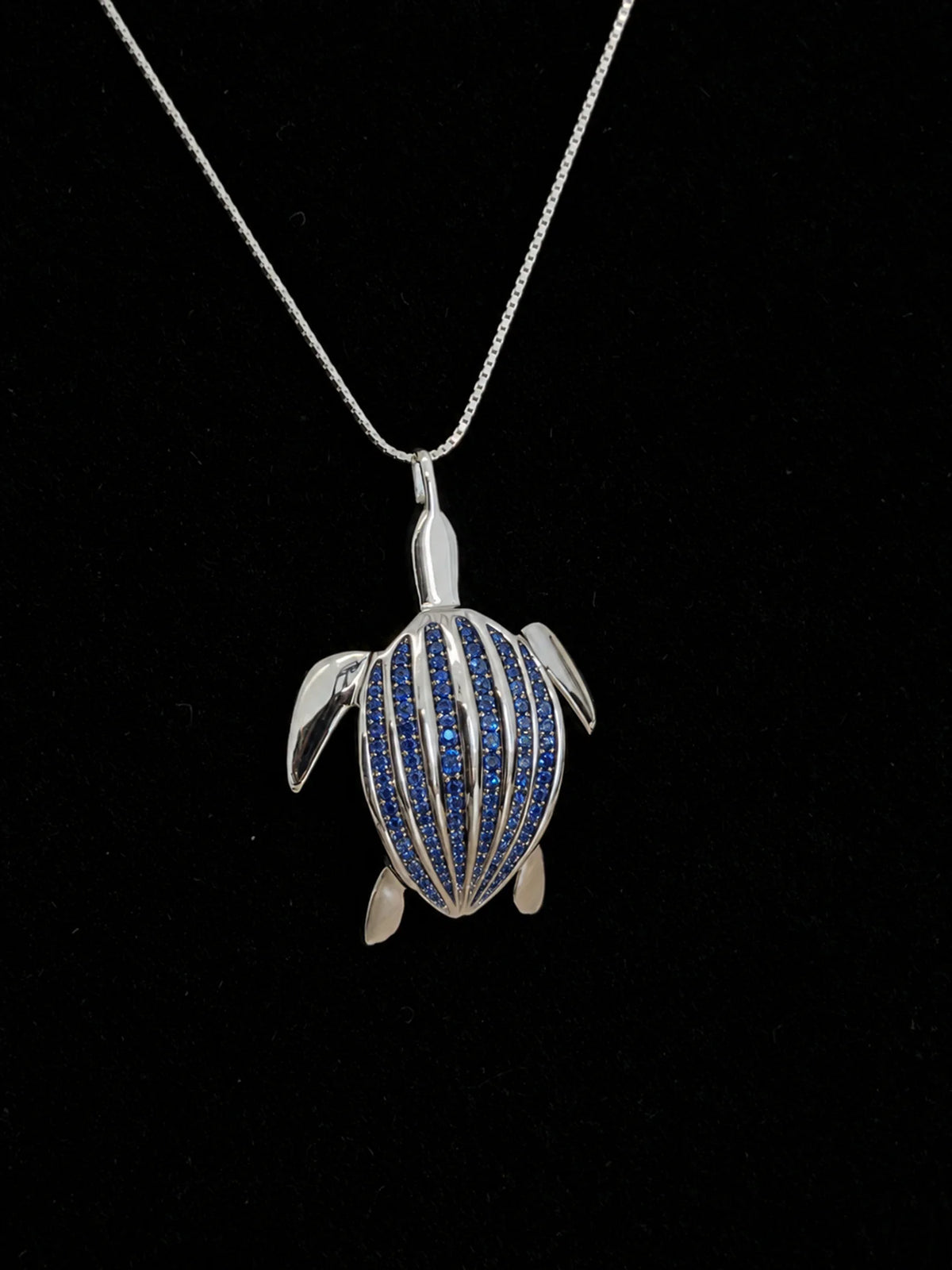 Le pendentif Totem Luth, saphirs bleus sur argent massif, en gros plan sur velours noir, carapace pavée détaillée | Honu