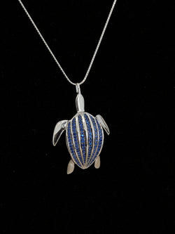 Le pendentif Totem Luth, saphirs bleus sur argent massif, en gros plan sur velours noir, carapace pavée détaillée | Honu